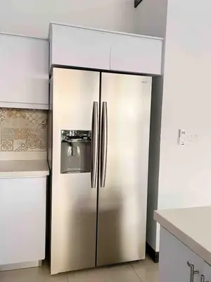 a stainless steel refrigerator in a kitchen with white cabinets at Beach House & Resort Amenities at Ciudad del Mar Jaco in Jacó