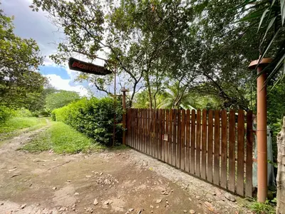 a fence with a sign on it next to a dirt road at Casona de Pani habitacion#3 in Liberia