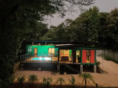 a house with a green facade with a deck at Pura Vida Jungle Container - Near Avellanas Beach in Tapantí
