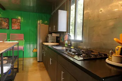 a kitchen with green walls and a stove top oven at Pura Vida Jungle Container - Near Avellanas Beach in Tapantí