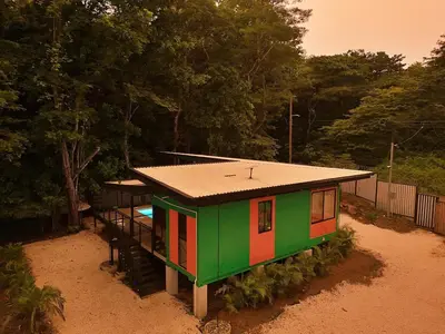 a small green and red house in the dirt at Pura Vida Jungle Container - Near Avellanas Beach in Tapantí