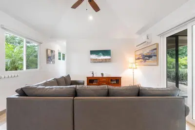 a living room with a large couch and windows at Beautiful Home in a Gated Neighborhood Walking Distance to the Beach with Garden Views and a Pool in Brasilito