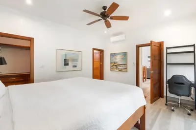 a bedroom with a white bed and a ceiling fan at Beautiful Home in a Gated Neighborhood Walking Distance to the Beach with Garden Views and a Pool in Brasilito