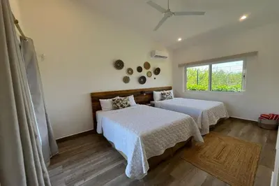 a bedroom with two beds and a window at Triskele Retreat - Casa Earth in Esterillos