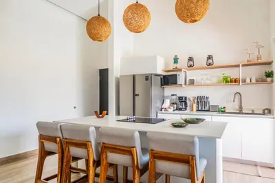 a kitchen with a white island with chairs around it at Triskele Retreat - Casa Earth in Esterillos