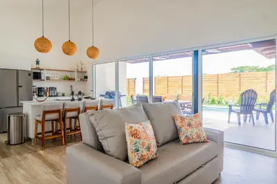 a living room with a couch and a kitchen at Triskele Retreat - Casa Earth in Esterillos