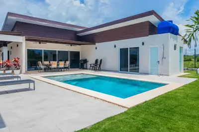 a villa with a swimming pool in front of a house at Triskele Retreat - Casa Ocean in Esterillos