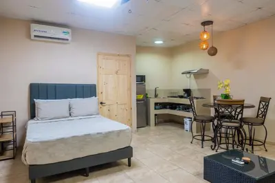 a bedroom with a bed and a table and a kitchen at Marsol 1 in Uvita