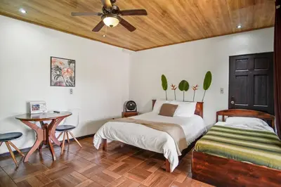 a bedroom with a bed and a table and a ceiling fan at Room J Heredia – Comfort and Excellent Location in Flor
