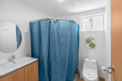 a bathroom with a blue shower curtain and a toilet at Contemporary Viva Jaco Residences Suite with Pool in Jacó
