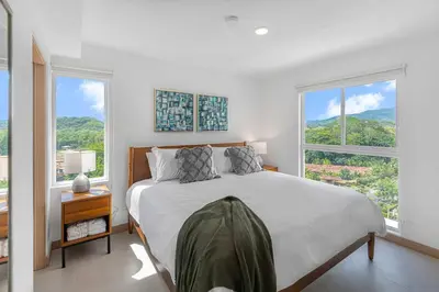 a white bedroom with a bed and two windows at Contemporary Viva Jaco Residences Suite with Pool in Jacó