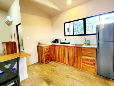 a kitchen with a stainless steel refrigerator and wooden cabinets at Nature Observatory Studio with Private Pool in Chachagua