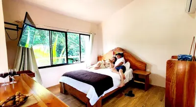 two people sitting on a bed in a bedroom at Nature Observatory Studio with Private Pool in Chachagua