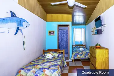 a bedroom with two beds and a fish on the wall at Blue Iguana in Sámara