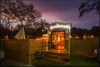a small cabin with lights on a fence at night at Casita VNV in Nosara
