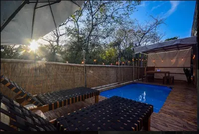 a swimming pool with benches and an umbrella at Casita VNV in Nosara
