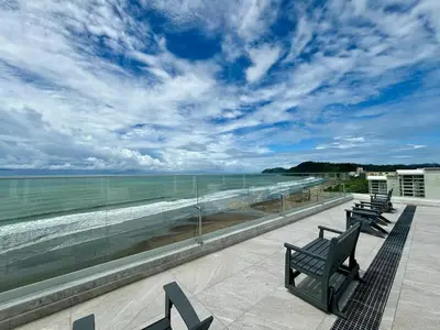 two benches sitting on a balcony looking at the ocean at Serene and Modern Beachfront Condo with Ocean Views in Jacó