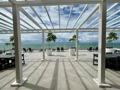 a pavilion with tables and palm trees on a beach at Serene and Modern Beachfront Condo with Ocean Views in Jacó