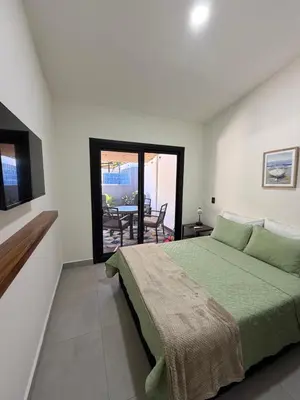 a bedroom with a bed and a television and a patio at House of the Orange Cat in Coco