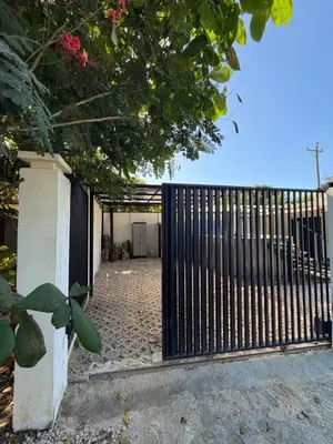 a gate to a house with a brick driveway at House of the Orange Cat in Coco