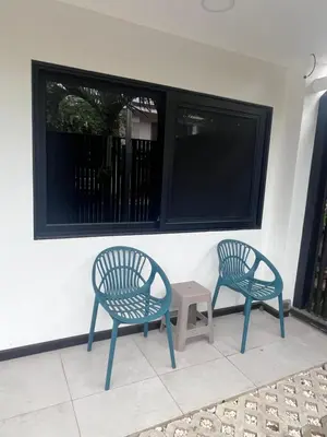 two chairs and a stool next to a window at House of the Orange Cat in Coco