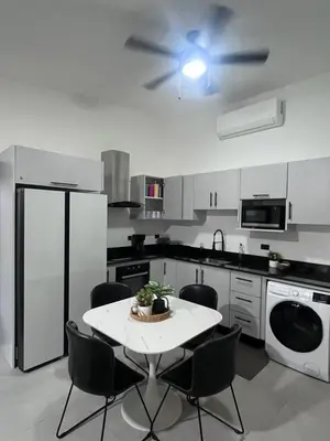 a kitchen with a table and a ceiling fan at House of the Orange Cat in Coco