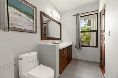 a bathroom with a toilet and a sink and a mirror at The Sky Deck Condo 2bed25bath in Coco