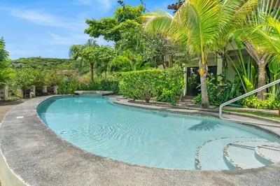 a swimming pool in front of a house with palm trees at The Sky Deck Condo 2bed25bath in Coco