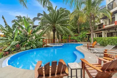 a swimming pool with chairs and palm trees at The Sky Deck Condo 2bed25bath in Coco