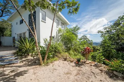 a white house with trees and plants in front of it at Villa Ocean Jungle View Infinity Pool Near Samara in Carrillo