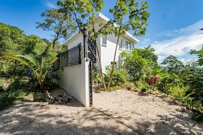 a white house with a gate in front of a yard at Villa Ocean Jungle View Infinity Pool Near Samara in Carrillo