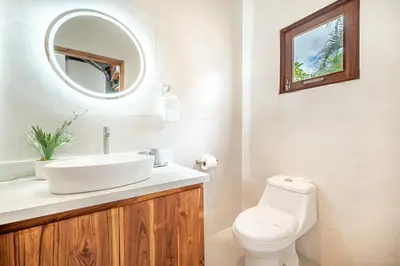 a bathroom with a sink and a toilet and a mirror at Villa Toscana Tamarindo- Elegant villa in Garita