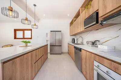 a kitchen with wooden cabinets and a stainless steel refrigerator at Villa Toscana Tamarindo- Elegant villa in Garita