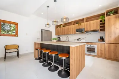 a kitchen with wooden cabinets and a counter with stools at Villa Toscana Tamarindo- Elegant villa in Garita