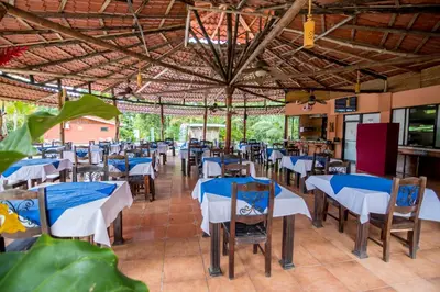 a restaurant with tables and chairs with blue and white tablecloths at Pacific Paradise Resort in Quepos