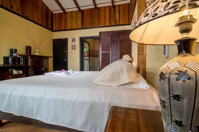 a bedroom with a large white bed with a lamp at Pacific Paradise Resort in Quepos