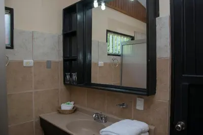 a bathroom with a sink and a mirror at Pacific Paradise Resort in Quepos