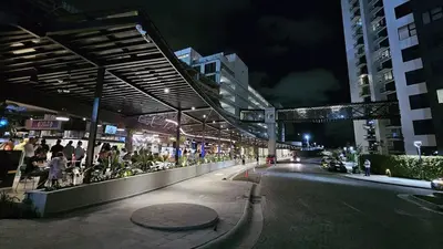 a city street at night with people sitting on a sidewalk at Apartment with air conditioning and 20 minutes from the airport in San José