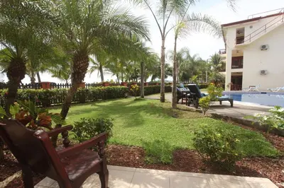 a yard with benches and trees and a swimming pool at Bahia Azul 3A in Jacó