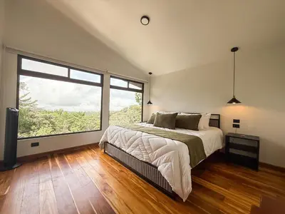 a bedroom with a bed and a large window at Casa Nara - Sunset View l Forest Deck - Mountain House in Monteverde Costa Rica