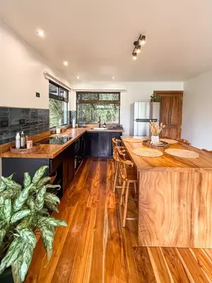 an open kitchen with wooden floors and a large island at Casa Nara - Sunset View l Forest Deck - Mountain House in Monteverde Costa Rica