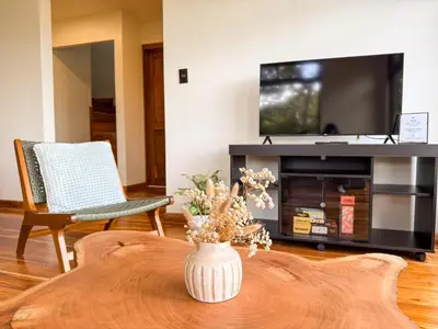 a living room with a tv and a table with flowers at Casa Nara - Sunset View l Forest Deck - Mountain House in Monteverde Costa Rica