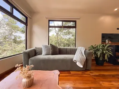 a living room with a couch and two windows at Casa Nara - Sunset View l Forest Deck - Mountain House in Monteverde Costa Rica