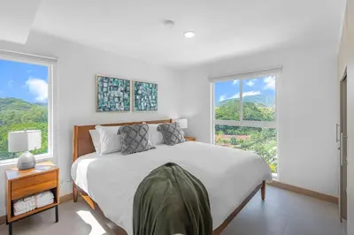 a white bedroom with a large bed and two windows at Upstay Brand New 3BR Viva Jaco Residences in Jacó
