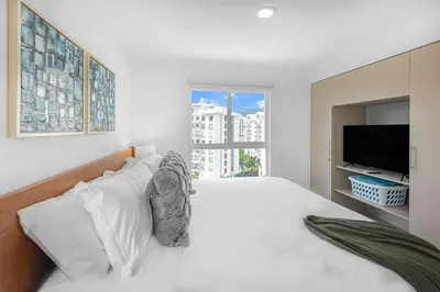 a white bedroom with a large bed and a tv at Upstay Brand New 3BR Viva Jaco Residences in Jacó