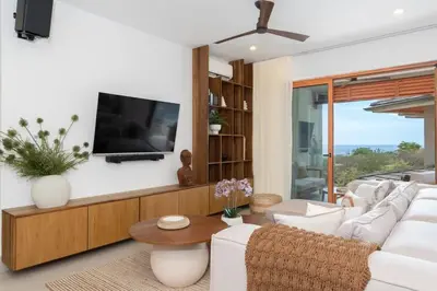 a living room with white furniture and a flat screen tv at Salty Living - Tamarindo Hills in Tamarindo