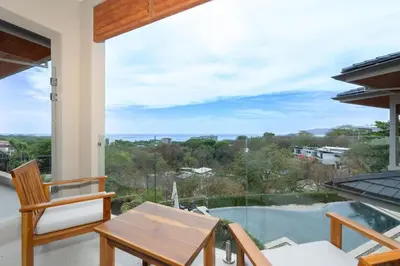 a view from the balcony of a house with a table and chairs at Salty Living - Tamarindo Hills in Tamarindo