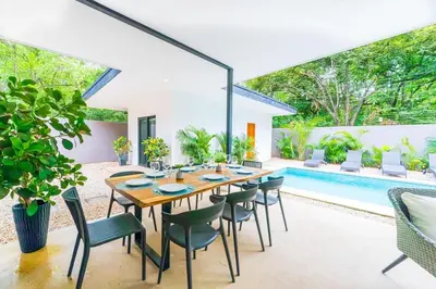 a dining room with a table and chairs and a pool at Serenity Surf Villa in Playa Grande