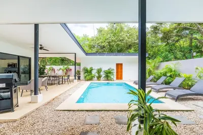 an open living room with a swimming pool and a house at Serenity Surf Villa in Playa Grande