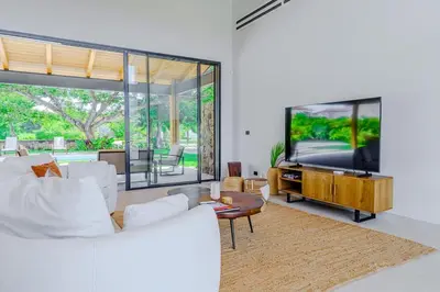 a living room with white furniture and a flat screen tv at Casa Nimbu - Hacienda Pinilla in Tamarindo